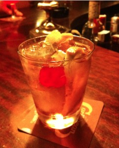 An Old Fashioned sits on fine-grained wood bar