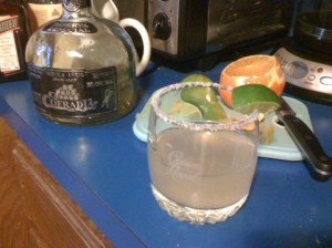 A rocks glass with salt on rim and a lime wedge. The glass contains a Margarita made with Cointreau and La Cofradia Añejo tequila