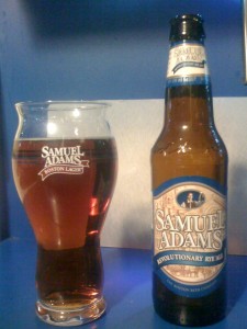 Samuel Adams Revolutionary Rye Ale poured into a glass, next to the bottle.