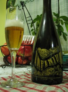 A fluted glass containing Samuel Adams Infinium next to a bottle of Samuel Adams Infinium
