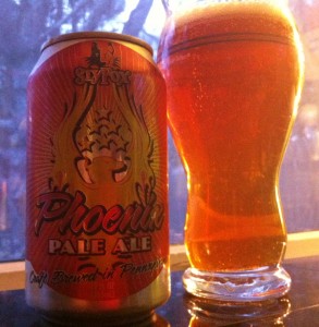 A can of SlyFox Phoenix Pale Ale and the beer poured into a pint glass. The beer is dark amber in color.