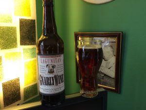 A bottle of Lagunitas GnarleyWine with a glass filled with the dark caramel-colored beer.