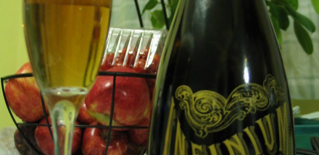 A fluted glass containing Samuel Adams Infinium next to a bottle of Samuel Adams Infinium