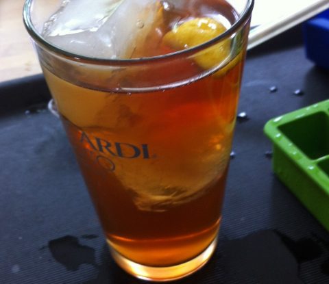 iced tea with large ice cubes and a slice of lemon in clear pint glass