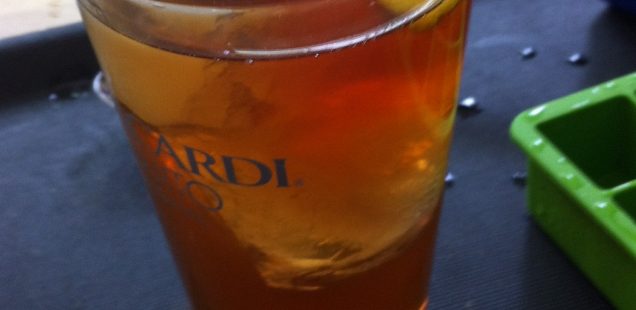 iced tea with large ice cubes and a slice of lemon in clear pint glass