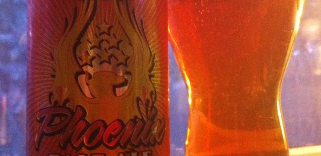 A can of SlyFox Phoenix Pale Ale and the beer poured into a pint glass. The beer is dark amber in color.
