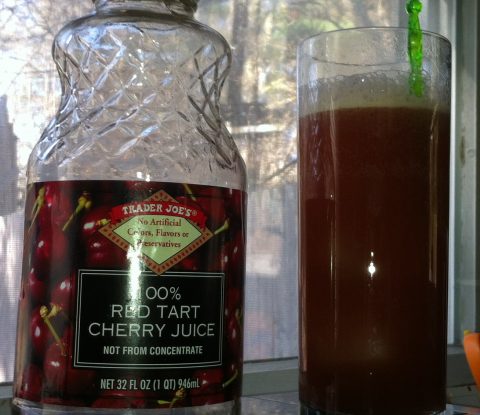 An empty bottle of Trader Joe’s 100 percent Red Tart Cherry Juice next to a Collins glass full with a Cherry lime Rickey