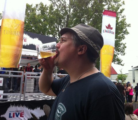 Fervere drinks from his glass Toronto’s Festival of Beer mug, in front of the Molson Canadian exhibition.