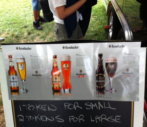 A pre-printed list displaying the three type of Krombacher beer, taped onto a sandwich board showing options for 1 token for a small serving and 2 tokens for a large.