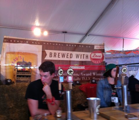 A cheeky gentleman and a woman stand behind the taps at Beau's All Natural station in Toronto’s Festival of Beer