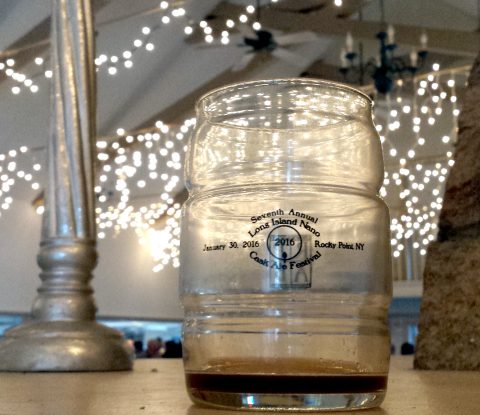 A cask shaped glass from the 2016 Long Island Nano Cask Ale Festival with a small amount of dark beer lingering in the glass